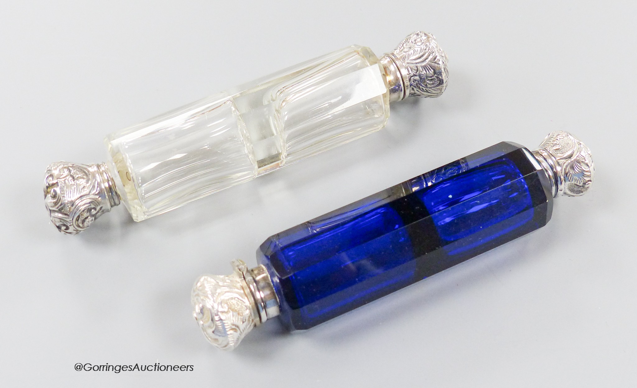 A late Victorian white metal mounted decagonal blue glass double ended scent bottle, 12.3cm (chip) and one other similar mounted clear glass scent bottle.